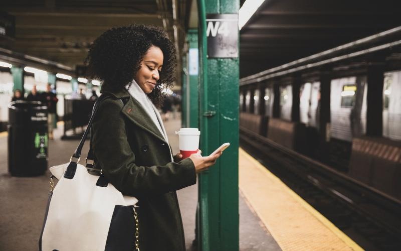 Find your perfect fit at Adenine woman with a cup of coffee texts on subway station platform